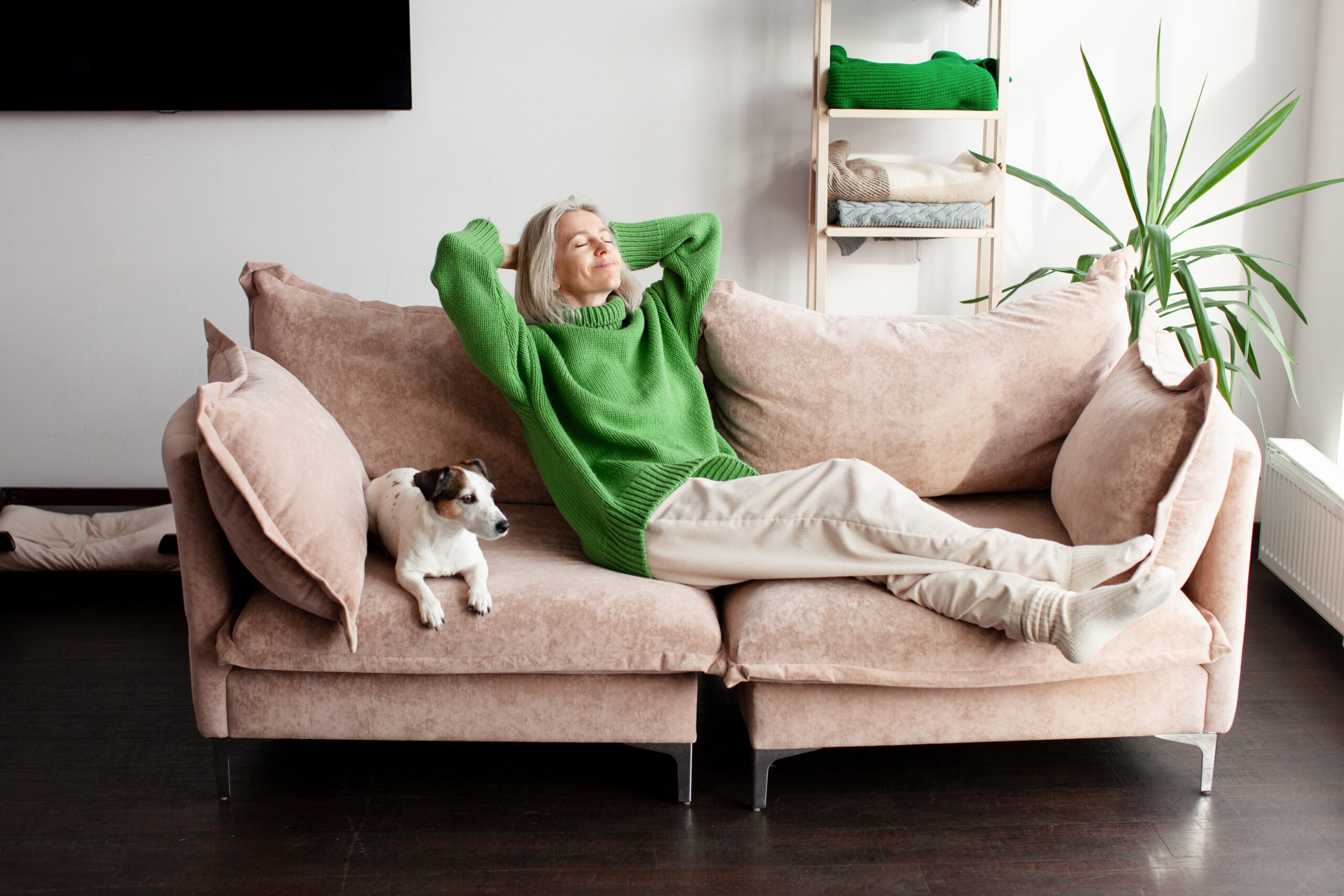 femme en vert assise sur un canapé avec un chien